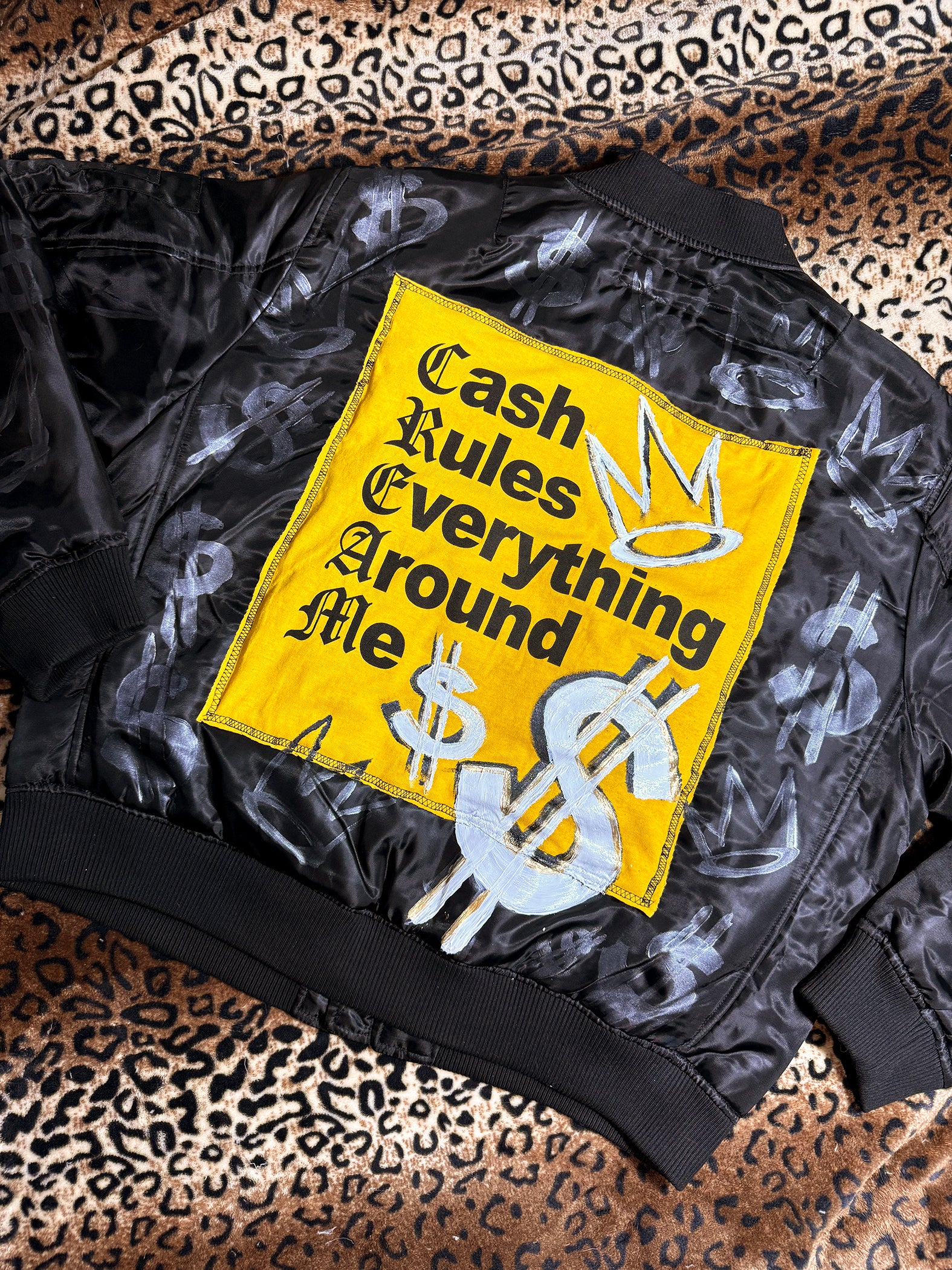 Black jacket with a yellow patch featuring text and symbols on a leopard print background