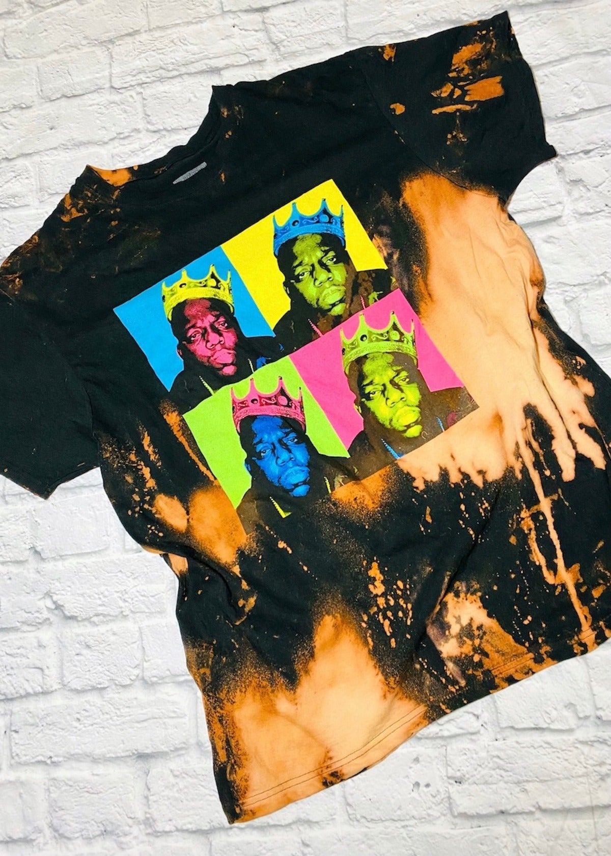 biggie bleach dye t shirt on a white brick background