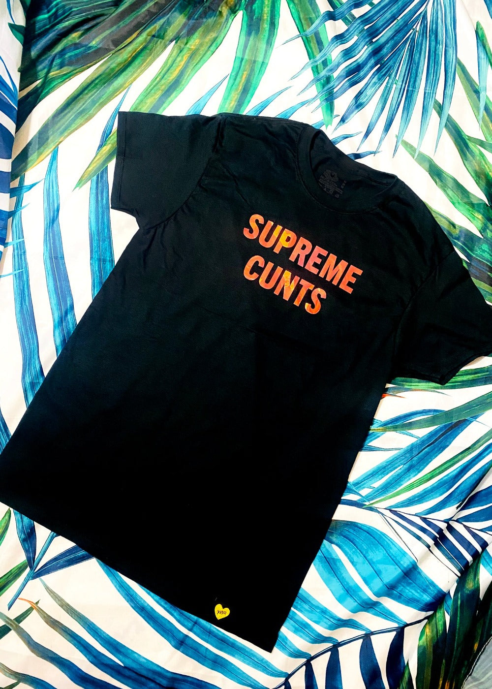 black graphic t shirt on a palm background full view