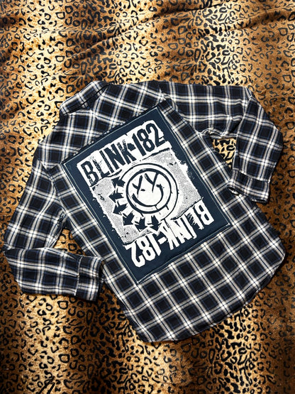Plaid shirt with Blink-182 logo on a leopard print background
