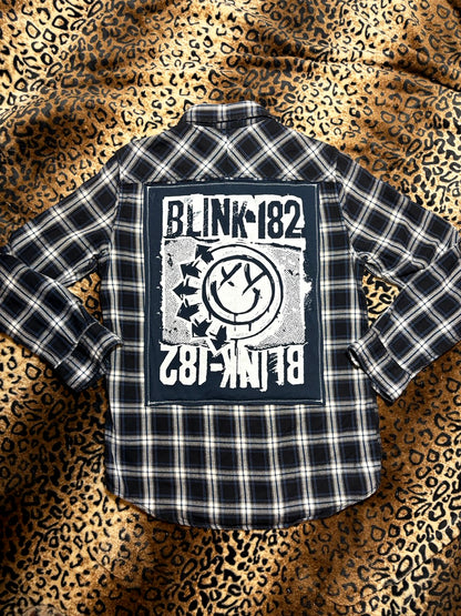 Black and white plaid shirt with Blink 182 logo on a leopard print background