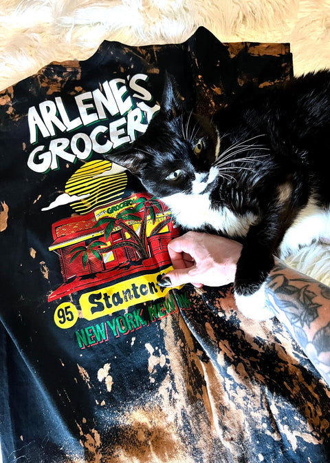 arlene's grocery bleach dye t shirt on a white furry rug with black and white cat