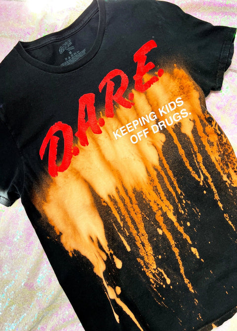 DARE bleach dye t shirt on a holo background close up