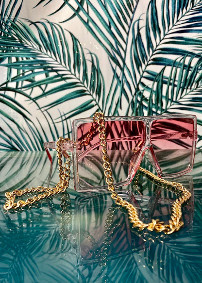 thich gold eyeglass chain on glass surface draped on pink glasses