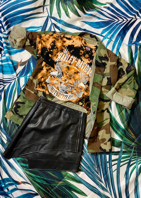 bleach dyed harley davidson crop top with black leather mini skirt and oversized camo jacket on a palm background 