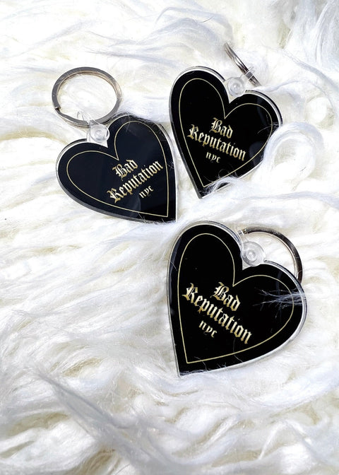 3 black heart keychains on white furry rug