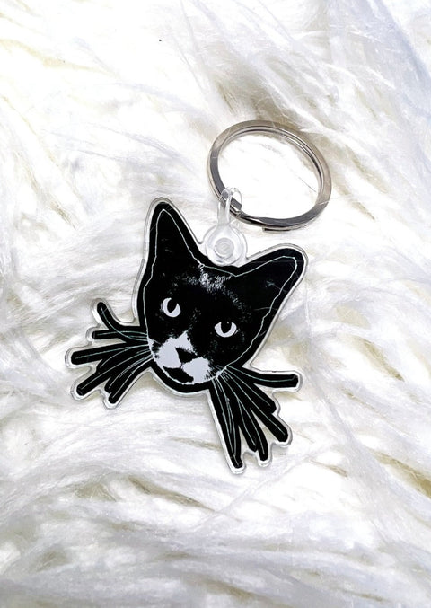 black cat face keychain on a white furry background